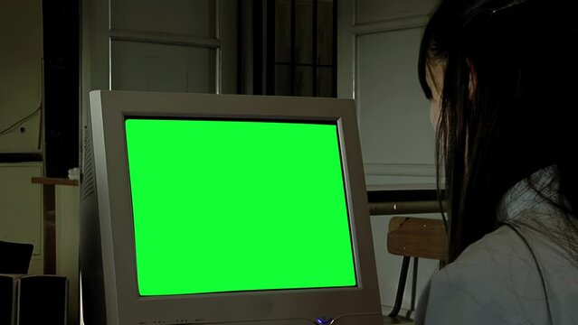 A Woman Looking At Computer Monitor with Green Screen in Dark Room. Close Up. You can replace green screen with the footage or picture you want with “Keying” effect in After Effects.