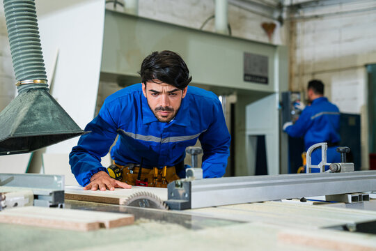 Modern industrial machine operator working in industrial factory. Woodworking carpenter furniture hand cutting. - Powered by Adobe