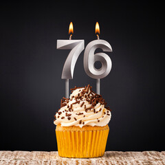 Birthday candle number 76 - Anniversary cupcake on black background