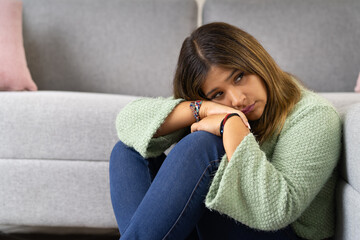 Sad woman sitting on the ground at home