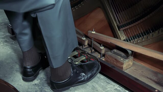Feet of a Senior Man Wearing Black Shoes Stepping on the Piano Pedals of an Old Piano. Close Up. 4K Resolution.