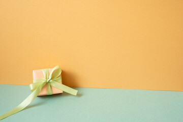 Coral gift box on mint green table. orange wall background. copy space