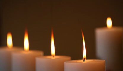 5 large white wax candles burning with long orange yellow flames. Five candle arrangement with a...
