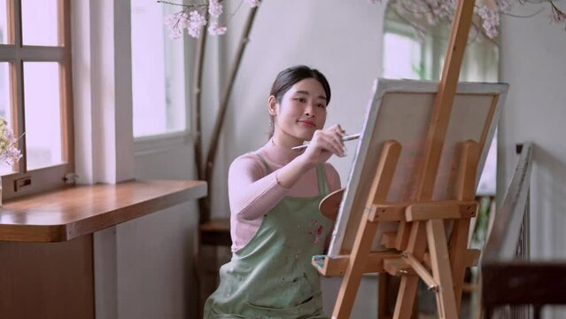 Asian woman artist working on painting brush on canvas and variant acrylic color in her art studio, Artist creative concept.