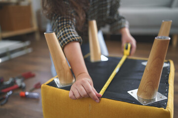 Women use measure tape equipment to measuring size of chair while assembling furniture for new home