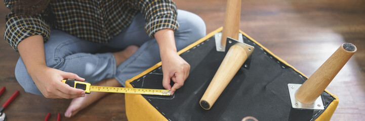 Women use measure tape equipment to measuring size for assembly leg of chair while making furniture