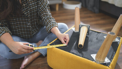 Women use measure tape equipment to measuring size for assembly leg of chair while making furniture