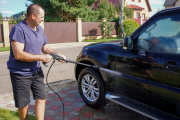 man washing car with car wash - pressure washer , shampoo, sponges and microfiber car towels
