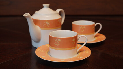 Teapot set as seen from above on a dark wood dining room table.