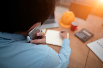Close up busy engineer contractor on business phone call while taking writing note using pen in...