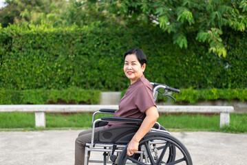Obraz premium Portrait of senior woman sitting on wheelchair at public park in the morning