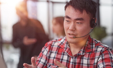 Obraz premium Young asian businessman working on laptop computer wearing headphone at home
