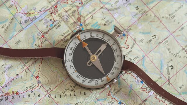 Old compass on map with mountain trails. Compass indicating north on map. Top down shot