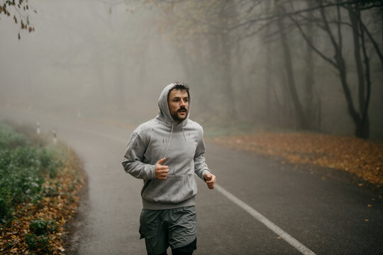A solo runner navigating a winding forest trail, the mist adding an air of solitude and intrigue.