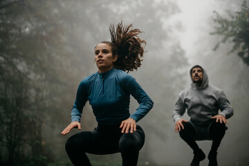 Two people in sports outfits warming up their legs by jumping before the running.