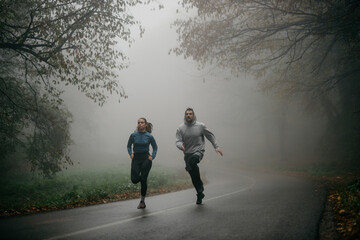 Two runners emerging from the mist-covered forest, creating an ethereal and enchanting scene.
