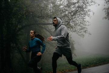 Two runners emerging from the mist-covered forest, creating an ethereal and enchanting scene.