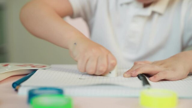 Little student removes bad picture with eraser at desk
