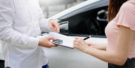 Automotive business, car sale or rental concept Customer with car dealer agent making deal and signing on agreement document contract in auto showroom or on road
