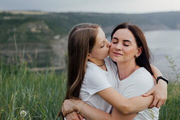 Mother and daughter. A mother hugs and kisses her daughter. Mother's Day. Caring for children.