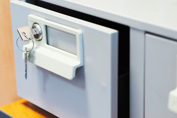 It is open gray document box with key in lock. Open cell drawer with personal files close-up....