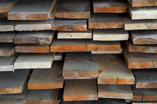 New planed wooden boards stacked in sawmill. Procurement and sale of building material. Dry wood. Woodworking. Background.