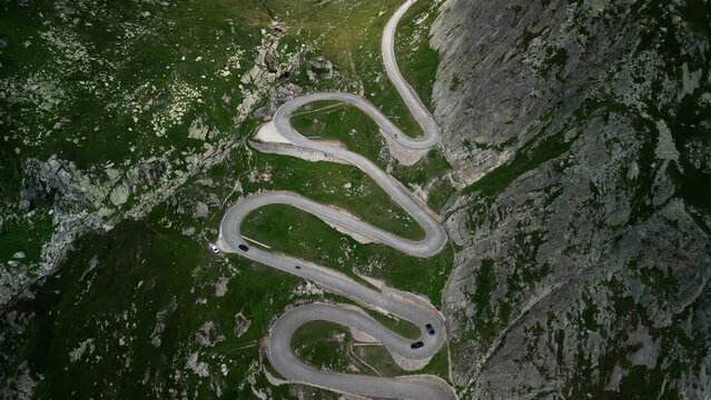 Slow aerial climb up a winding road to the Grimselpass in the Swiss Alps. Taken from a drone at high altitude, sunny day