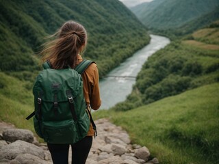 a beautiful girl hiking in mountains, with green grass looking at beautiful mountain valley And river  at early morning in summer. Landscape with sporty young woman, rear view - obrazy, fototapety, plakaty