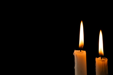 Two lit white candles with copy space on black background