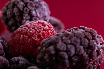 Micro close up of frozen raspberries with copy space on red background