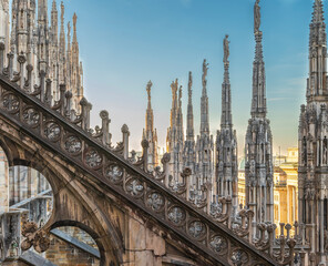 Fototapeta na wymiar Flying buttress and rows of pinnacle sculptures on the rooftop aisle of Milan Cathedral