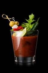 Bloody mary cocktail mix with red and green pepper and olive, celery,olives and lime slice on black background.