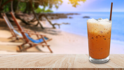 Iced thai milk tea in glass, Milk ice tea, Cheddar is a traditional Thai drink on wooden table with beach landscape nature background, Summer drinks with iced