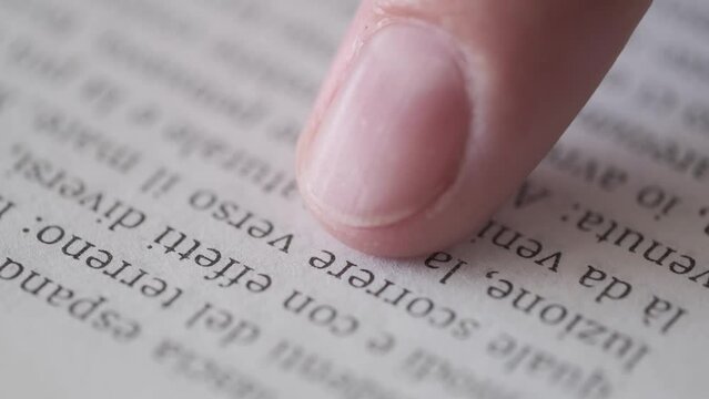 
Book reading. Closeup text in book,  woman reading the italian text following  finger. Reading literature and education. shallow depth of field. Macro.
