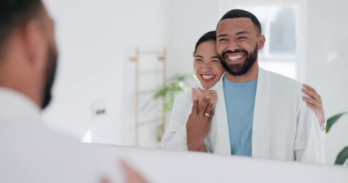 Love, hug and happy couple in the bathroom for health, wellness and morning routine together. Smile, mirror and interracial man and woman embracing before self care treatment at modern apartment.