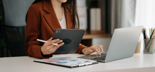 Confident Asian woman with a smile standing holding notepad and tablet at the modern office.