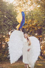 Beautiful girl angel in the evening garden with Ukrainian flag