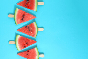 Watermelon on a wooden ice cream stick on a blue background. Creative food concept.