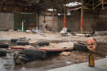 Scène d'horreur dans une usine abandonnée. Une tête de poupée sur une bouteille de bière....