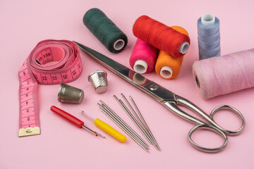 various tailor accessories and tools for tailoring on a pink background