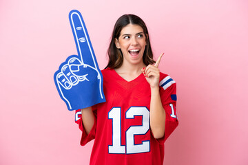 Young Italian fan woman with foam hand isolated on pink background thinking an idea pointing the...