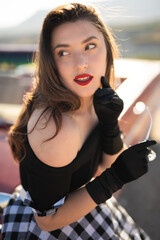 beautiful girl in retro style posing near vintage red cabriolet car.