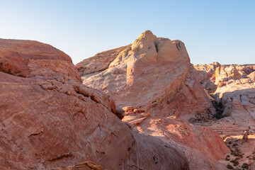 Fototapeta na wymiar Panoramic sunrise view of arid landscape with striated red and white rock formations along the White Domes Hiking Trail in Valley of Fire State Park in Mojave desert, Overton, Nevada, USA. Road trip