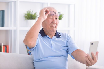 Presbyopia, senior asian man holding eyeglasses having problem with vision problem trying to read...