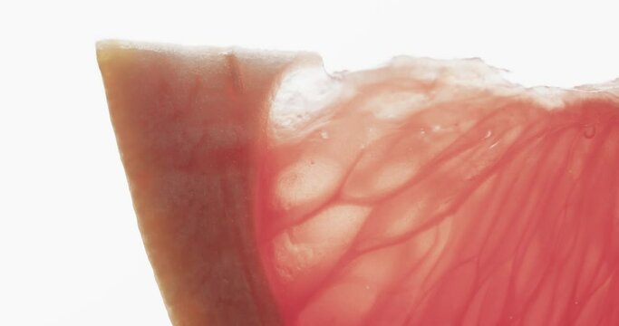 Micro video of close up of red grapefruit slice with copy space on white background