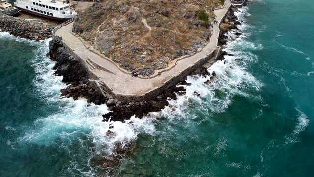 Large waves splashing at the rocks in Agios Nikolaos in Greece. Drone panning shot