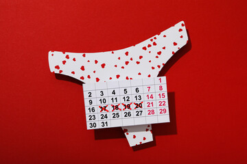 Panties and calendar  for menstruation on a red background