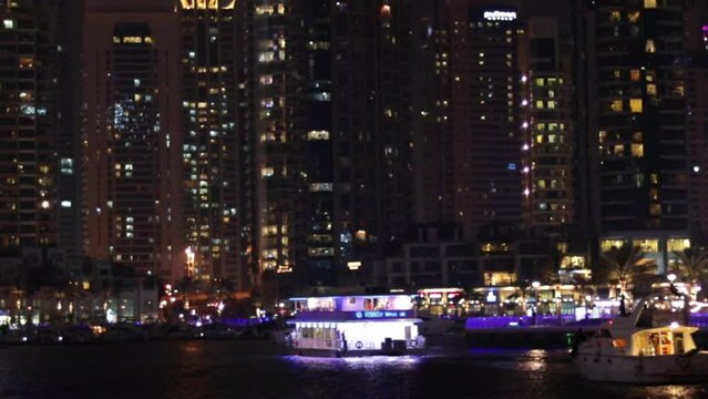 The yacht sails with tourists on board at night along the marina. High quality 4k footage