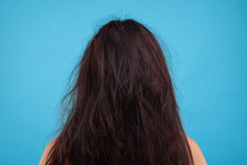 Woman with damaged hair on light blue background, back view