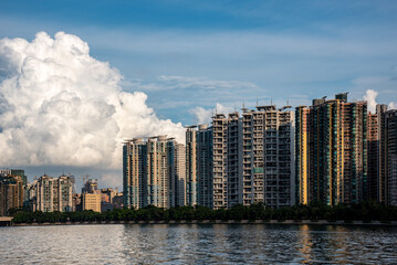 High rise buildings on the river bank under blue sky with white clouds. Residential buildings by the river. Cityscape of haizhu district, Guangzhou, China. 